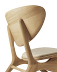 The Eye Lounge Chair by Ethnicraft features oak construction, a curved backrest, angled legs, and off-white fabric upholstery, showcased against a white background.