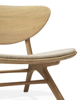 A close-up of the Eye Lounge Chair - Oak with Off White Fabric by Ethnicraft highlights its curved backrest and woven seat detail in a light wood finish, set against a plain white background.