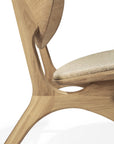 Close-up of the Ethnicraft Eye Lounge Chair in oak with off white fabric, featuring solid wood, smooth curved lines, and natural wood grain details against a white background.