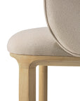 Close-up of the Ethnicraft Unda Dining Chair by Studio Segers, featuring a light wood frame and legs, with a rounded upholstered shell seat and backrest in beige fabric for smooth lines and soft texture.