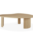 The Boomerang Coffee Table - Oak by Ethnicraft features a modern, organic-shaped solid oak top and three unique legs—including one rounded with vertical grooves—showcasing classic European-inspired design.