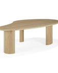 The Ethnicraft Boomerang Coffee Table - Oak features an organic, asymmetrical solid oak top with a smooth, light finish and three thick fluted legs, inspired by classic European design and reminiscent of Ethnicraft’s signature style.