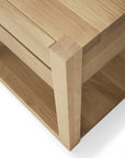 Close-up view of the Ethnicraft Azur Nightstand, a modern rectangular piece in European oak. The image shows its corner joint and part of the lower shelf, with light wood grain and a hardwax oil finish highlighting fine craftsmanship.