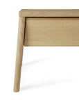 Close-up of the Ethnicraft Air Nightstand—a light wood piece with a minimalist design—highlighting its corner and two angled legs against a white background.