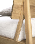 Close-up of the Ethnicraft Air Bed, featuring a slanted headboard in light European oak. A white mattress and textured gray pillow are partly visible. The modern, minimalist design highlights quality craftsmanship.