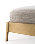Close-up of the Ethnicraft Air Bed, featuring a corner of its European oak frame with clean lines and a low, modern profile. A mattress in textured light beige fabric rests atop, set against a plain white background.