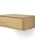 The Ethnicraft Nordic II Hanging Bedside Table is a solid European oak floating shelf with a single drawer and clean lines, showcasing minimalist elegance against a plain white background.