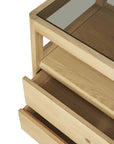A close-up of the Ethnicraft Spindle Dresser in oak—a light wood piece with a glass top and two open drawers, exemplifying simple modern design and clean lines.