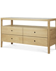 The Ethnicraft Spindle Dresser - Oak features four drawers, an open top shelf, minimalist design, and round handles. This elegant light wood piece stands on four legs and is part of the Spindle collection.