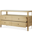 The Ethnicraft Spindle Dresser in oak features a minimalist design with an open top shelf, four drawers, and round cut-out handles.