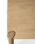 Close-up of the Ethnicraft PI Dining Table - Oak, featuring a smooth solid oak tabletop, one rounded corner, a tapered leg with visible wooden joint, and clearly defined wood grain and clean finish.