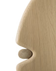 A close-up of the Ethnicraft Pi Side Table - Oak shows its carved solid oak surface, shaped like a face in profile with a small round wooden detail as the nose, highlighting the table’s unique artistic design.