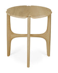 The Ethnicraft Pi Side Table - Oak is a small, round table with three legs and a smooth solid oak finish. Its tabletop has gentle, organic curves inspired by clover leaves.
