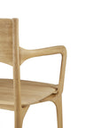 A close-up of the Ethnicraft PI Dining Chair - Oak with arms reveals its curved armrest, smooth natural finish, and part of the backrest and seat, highlighting the elegant craftsmanship of this solid oak chair.
