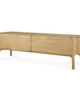 The Ethnicraft PI TV Cupboard is a minimalist sideboard crafted from solid oak, featuring two large doors, a smooth top, and rounded legs in a light natural finish.
