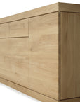 The Ethnicraft Burger Sideboard is a modern wooden cabinet crafted from solid oak with a light natural finish, featuring handleless flat panel doors and drawers, shown angled to display its side and front.