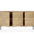 The Ethnicraft Whitebird Sideboard - 3 door is a modern solid oak piece with a light finish, interior shelves behind three cabinet doors, and slim black metal legs.