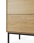 Close-up of the Ethnicraft Whitebird TV Cupboard, a modern piece in solid oak with a natural finish. It has two drawers, black cylindrical legs, and visible wood grain for a minimalist, contemporary Ethnicraft-inspired look.