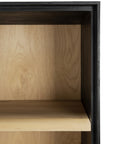 Close-up of the Ethnicraft Blackbird Storage Cupboard, featuring a light European oak shelf corner. The black-painted frame creates a bold contrast and highlights the refined craftsmanship of this contemporary piece.