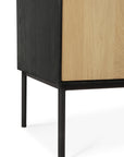 Close-up of the corner of Ethnicraft’s Blackbird Storage Cupboard, showcasing its black legs and light European oak front panel against a white background.