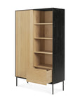 The Blackbird Storage Cupboard by Ethnicraft features European oak with black sides, two doors (one open to shelves), a lower drawer pulled out, and metal legs—offering a minimalist modern design.