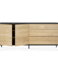 The Ethnicraft Blackbird Sideboard features a light European oak finish, black top and legs, two doors with spacious shelves on the left, and three drawers on the right for ample storage.