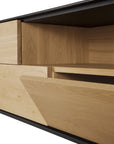 Close-up of the Ethnicraft Blackbird TV Cupboard, showcasing clean lines, European oak grain, and minimalist black accents with a focus on the geometric design of its drawers and panels.