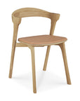 The Ethnicraft Bok Dining Chair features solid oak construction, a curved backrest, four legs, and a Sienna leather upholstered seat.