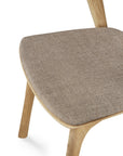 Close-up of the Ethnicraft Bok Dining Chair—oak frame with angled legs and warm grey textured fabric upholstery.