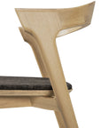 Close-up of the Ethnicraft Bok Dining Chair - Oak with Dark Brown Fabric, a modern solid oak piece featuring angular backrest and armrests and a dark upholstered seat cushion.