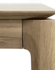 Close-up of the Ethnicraft Bok Extendable Dining Table - Oak, highlighting its natural oak grain, rounded legs, and thick tabletop with a smooth, modern finish.
