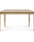 The Bok Dining Table - Varnished Oak by Ethnicraft is a rectangular solid oak table with four straight legs, shown from the short end against a white background. Its design is simple, modern, and features a natural varnished wood finish.