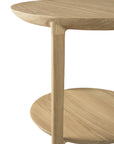 Close-up of the Ethnicraft Bok Side Table - Oak, crafted from solid oak with two round shelves and smooth, rounded edges, highlighting its minimalist design against a white background.