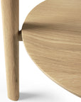 Close-up of the Ethnicraft Bok Side Table - Oak, featuring a round solid oak tabletop with visible grain and a cylindrical leg intersecting the edge, set against a white background.