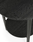 A close-up of the Ethnicraft Bok Side Table - Black shows its two tiers crafted from black solid oak, highlighting the tabletop and lower shelf with their distinct wood grain texture.