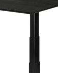 A close-up of the corner and leg of the Bok Adjustable Desk - Black Oak by Ethnicraft showcases its modern, minimalist design against a white background.