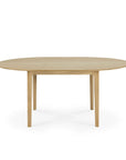 The Ethnicraft Bok Round Extendable Dining Table in oak features a simple, minimalist design with four straight legs and is shown from the front against a white background.