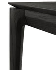 Close-up of the Bok Bench - Black Oak by Ethnicraft, highlighting the tabletop, angled leg, and visible European oak wood grain in a black varnished finish.