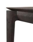 Close-up view of the corner of the Ethnicraft Bok Bench in brown oak, highlighting the tabletop and a leg with clean, modern lines and a smooth finish.