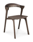 The Ethnicraft Bok Dining Chair in brown oak features solid oak construction, a curved backrest, angled legs, and a minimalist contoured seat for modern style.