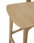 Close-up view of the Ethnicraft Bok Counter Stool, featuring a smooth, light-toned seat and simple lines. Its gently curved legs and minimalist design emphasize the modern elegance of this wooden stool.