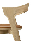 Side view of the Ethnicraft Bok Barstool - Oak, featuring a curved backrest, light brown leather seat, clean lines, solid oak construction, and visible natural wood grain.