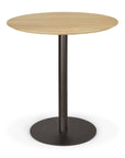 The Ethnicraft Blend Dining Table - Oak features a light solid oak round top with a single black metal pedestal leg and circular base.