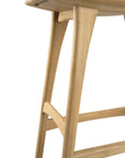 Close-up of the Osso Barstool - Oak by Ethnicraft, highlighting its smooth curved seat, angled legs, and crossbars. The natural solid oak grain and minimalist European design stand out against a crisp white background.
