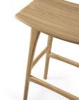 A close-up of the Osso Barstool - Oak by Ethnicraft highlights the smooth finish, natural solid oak grain, and elegant European design features of its seat, legs, and support bars.
