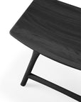 Close-up of the corner of an Ethnicraft Osso Dining Stool in black, crafted from solid oak with curved edges and visible wood grain, set against a white background.