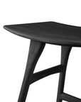 A close-up of the Ethnicraft Osso Dining Stool - Black, crafted from black stained solid oak with a smooth contoured seat and angled legs, set against a white background.
