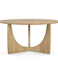 The Ethnicraft Geometric Dining Table - Oak features a smooth, round solid oak top and a unique base with two curved intersecting panels for a sculptural, modern look.