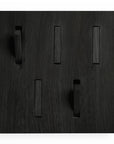 The Utilitile Wall Hanger by Ethnicraft features a black wooden panel with five rectangular cutouts and three protruding blocks, creating a minimalist geometric pattern—perfect as a modern coat hanger.