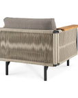 The Ethnicraft Corbey Outdoor Lounge Chair features a woven rope back and sides, black metal legs, wooden armrests, and a gray cushion—an inviting modern piece pictured from the back at an angle.